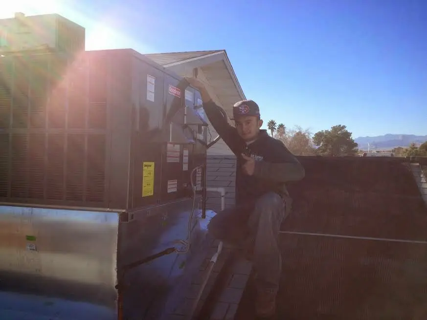 HVAC technician performing Air Duct Cleaning on a rooftop unit in Westland